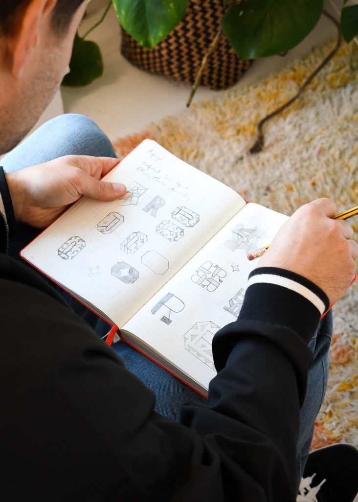 The process of brand design. Devon based designer Dennis Cook sketches logo design ideas in his note book.