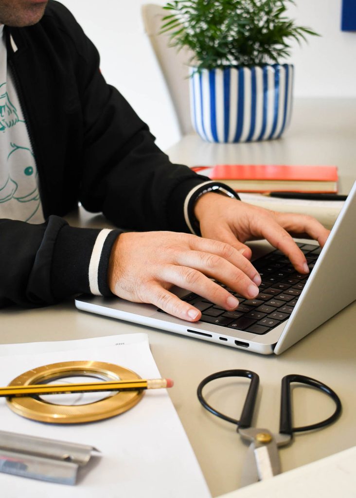 Focussed on a piece of digital design, Exeter graphic designer Dennis Cook sits at his laptop in a well like Devon studio.