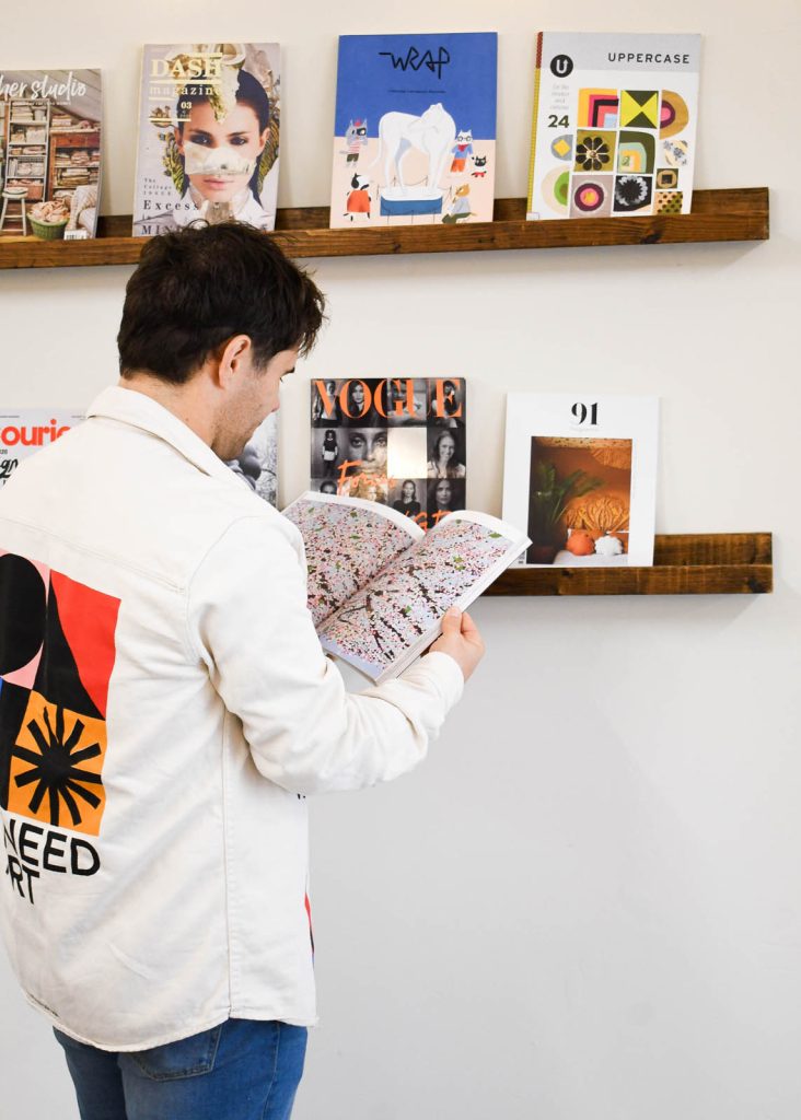 Dennis Cook, senior graphic design and creative director of DC Design works, reads a colourful magazine while stood up. He is a graphic designer Devon businesses can turn to for their branding and communication needs.
