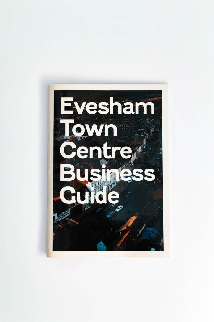 A portrait photograph of the front cover of the Evesham Town Centre Business Guide, featuring an aerial photo of Evesham high street. Designed by DC Design Works: graphic design studio, Devon.